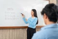 Female tutor standing in front of whiteboard and writing math equations on board to explaining for student Royalty Free Stock Photo