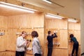 Female Tutor With Trainee Electricians In Workshop Studying For Apprenticeship At College