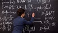 Female tutor writing formula on chalkboard, mathematics lecture, exact sciences