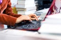 Female typing on laptop keyboard surrounded by books and files Royalty Free Stock Photo