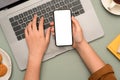 A female typing on notebook laptop and holding a smartphone over her desk Royalty Free Stock Photo