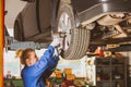 Female tyre service worker fixing wheels on lifted car