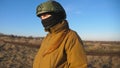 Female ukrainian army soldier walking at the field. Woman in military uniform and helmet going on meadow at sunset