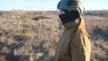 Female ukrainian army soldier walking at the field. Woman in military uniform and helmet going on meadow at sunset