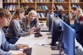 Female University Or College Student Working At Computer In Library Being Helped By Tutor Royalty Free Stock Photo