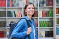 Female university student with backpack, inside library of educational building Royalty Free Stock Photo