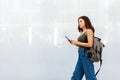 Female university student with backpack walking in campus. Young woman in city street using mobile phone. Copy space. Royalty Free Stock Photo