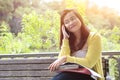 Female university student using her phone, sitting on wooden bench in a park. Royalty Free Stock Photo