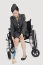 Female US Military Officer In Wheelchair Holding Artificial Limb Over Gray Backgrounds
