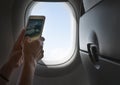 Female using her smartphone for photographing clouds and aircraft engine through the porthole. Active traveling and flying by