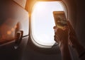 Female using her smartphone for photographing clouds and aircraft engine through the porthole. Active traveling and flying by