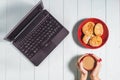 Female using laptop with a coffee cup on wooden table.