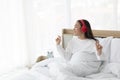 Female using red headphone on bed at home. Young girl wearing pajamas sitting on bed at bedroom  listening to music with headphone Royalty Free Stock Photo