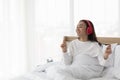 Female using red headphone on bed at home. Young girl wearing pajamas sitting on bed at bedroom  listening to music with headphone Royalty Free Stock Photo