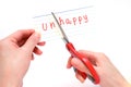 Female using scissors to remove the word unhappy to read happy