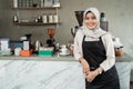 Female veiled waitress with lean back arm standing at workplace