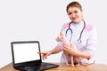 Female vet showing forefinger to empty mock up laptop screen. Veterinary clinic website on laptop display. Doctors for