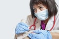 Female veterinarian cleaning injury on dog's leg with stick bud over gray background