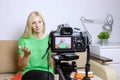 Female video blogger recording vlog or podcast, streaming online. Blurred camera on tripod in front. Royalty Free Stock Photo