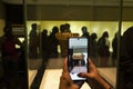 Female visitor taking a picture with a smartphone to an ancient golden piece