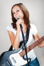 Female vocalist with microphone and bass guitar on gray Royalty Free Stock Photo