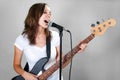 Female vocalist with microphone and bass guitar on gray Royalty Free Stock Photo