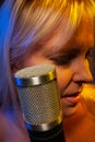 Female vocalist under gelled lighting with condenser microphone