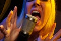 Female vocalist under gel lighting sings with passion into condenser microphone