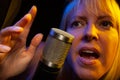 Female vocalist under gel lighting sings with passion into condenser microphone