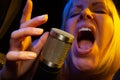 Female vocalist under gelled lighting sings with passion into condenser microphone