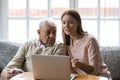 Female volunteer assisting elderly man in shopping online using computer