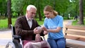 Female volunteer helping disabled old man use smartphone, nursing home charity