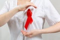 A female volunteer in a medical gown shows a red ribbon on her chest with her hands. Close up. The concept of world AIDS day Royalty Free Stock Photo