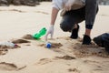 Female volunteer picking up trash and plastics, cleaning beach with a garbage bag, copy space Royalty Free Stock Photo