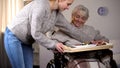 Female volunteer serving dinner to handicapped old woman, elder care, help Royalty Free Stock Photo