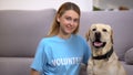 Female volunteer sitting near cute homeless labrador dog social adoption program