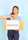 a female volunteer wears blue T-shirt holding donation box,woman hand giving banknote into donation box Royalty Free Stock Photo