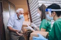 Female volunteers in mask gives an elderly man boxes with food near his house. Quarantined, . Coronavirus covid-19.