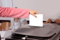 Female voter throws a ballot paper into a gray ballot box at a polling station in Germany, hand with paper close-up, concept of