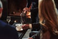 Female waiter pouring hot tea in the white cup. Friends sits in the restaurant with beautiful fireplace in it Royalty Free Stock Photo