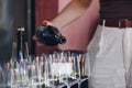 Female waiter pouring sparkling wine to the glass on the bar table, close up without face.