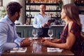 Female Waitress With Digital Tablet Taking Order From Romantic Couple Sitting At Restaurant Table