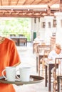 Female waitress holding a tray of coffee cups at interior of a summer open air restaurant. Khao Lak beach, Phang Nga, Thailand