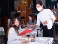 Smiling female waiter taking order from woman in restaurante diring virus Royalty Free Stock Photo