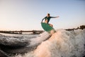 female wakesurfer skilfully jumping on wakesurf over great splashing river wave
