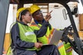 Female warehouse logistic staff with male worker driving a forklift working at shipping cargo Royalty Free Stock Photo