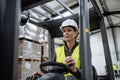 Female warehouse worker driving forklift. Warehouse worker preparing products for shipmennt, delivery, checking stock in Royalty Free Stock Photo