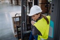 Female warehouse worker driving forklift. Warehouse worker preparing products for shipmennt, delivery, checking stock in Royalty Free Stock Photo