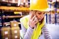 Female warehouse worker with smartphone.