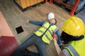 A female warehouse worker using a walkie-talkie called the factory's first aid team to rescue an unconscious man Royalty Free Stock Photo